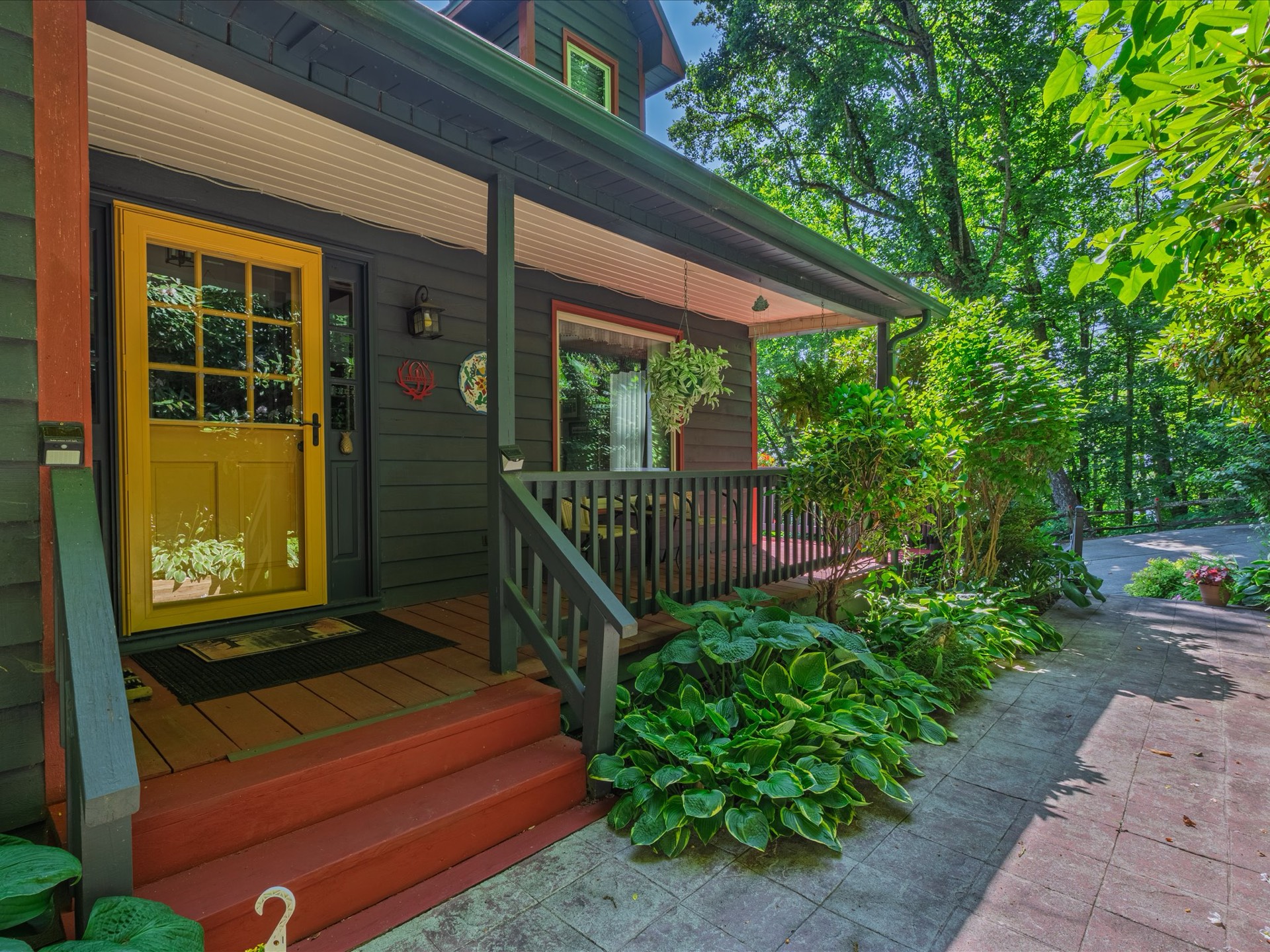 Covered front porch with yellow door and garden
