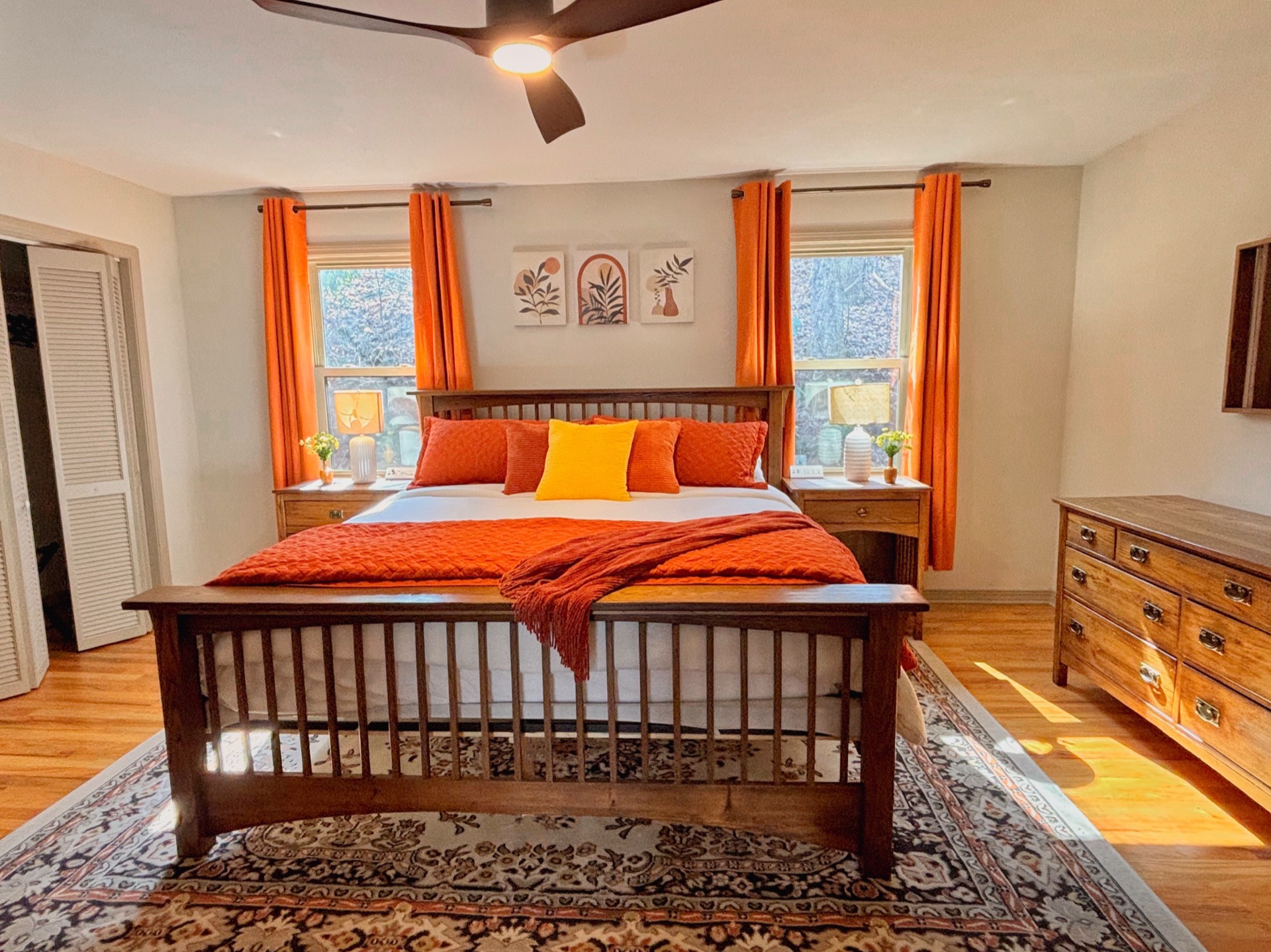 Master bedroom with orange curtains and ceiling fan