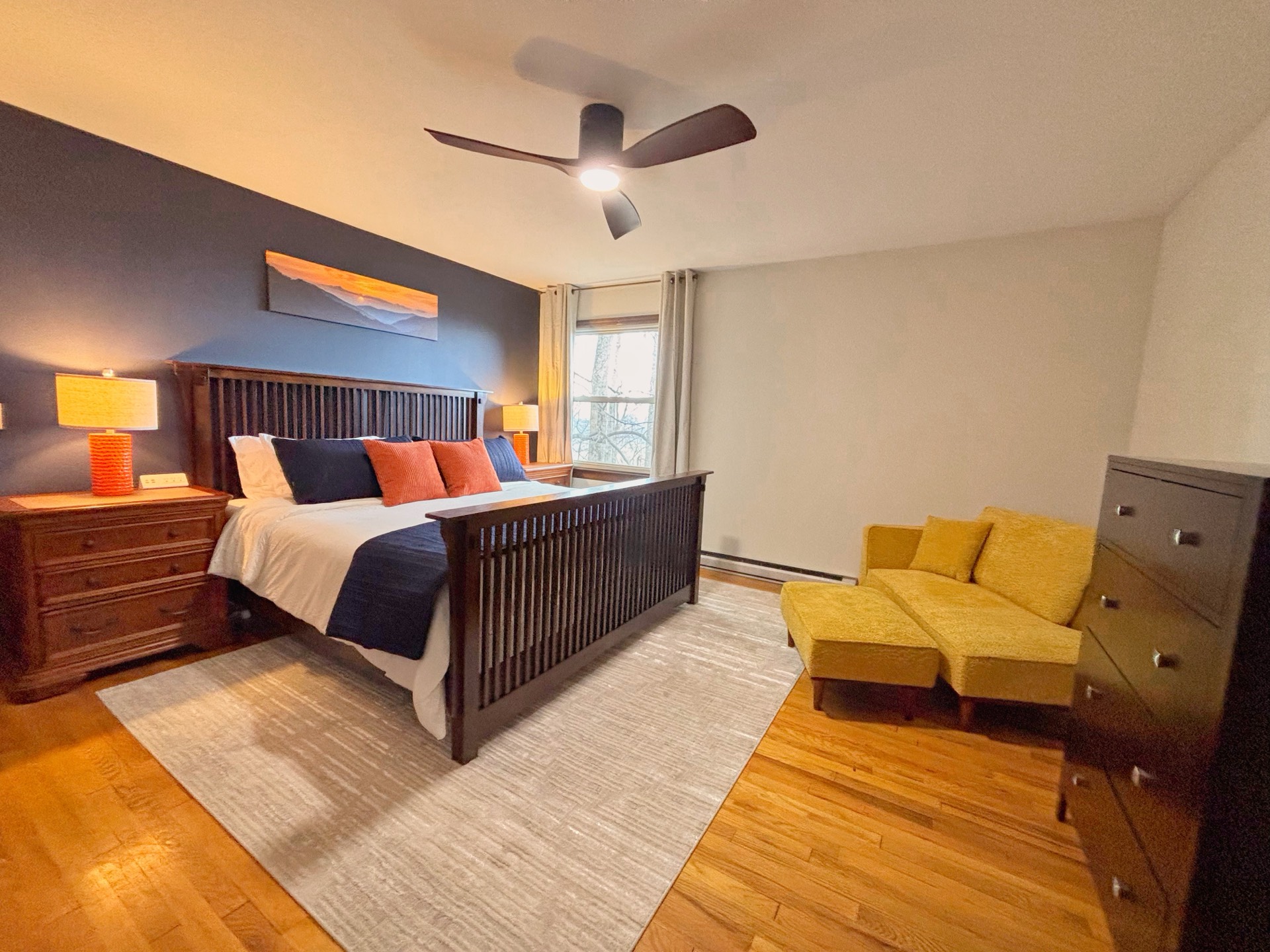 Spacious bedroom with navy wall and yellow loveseat