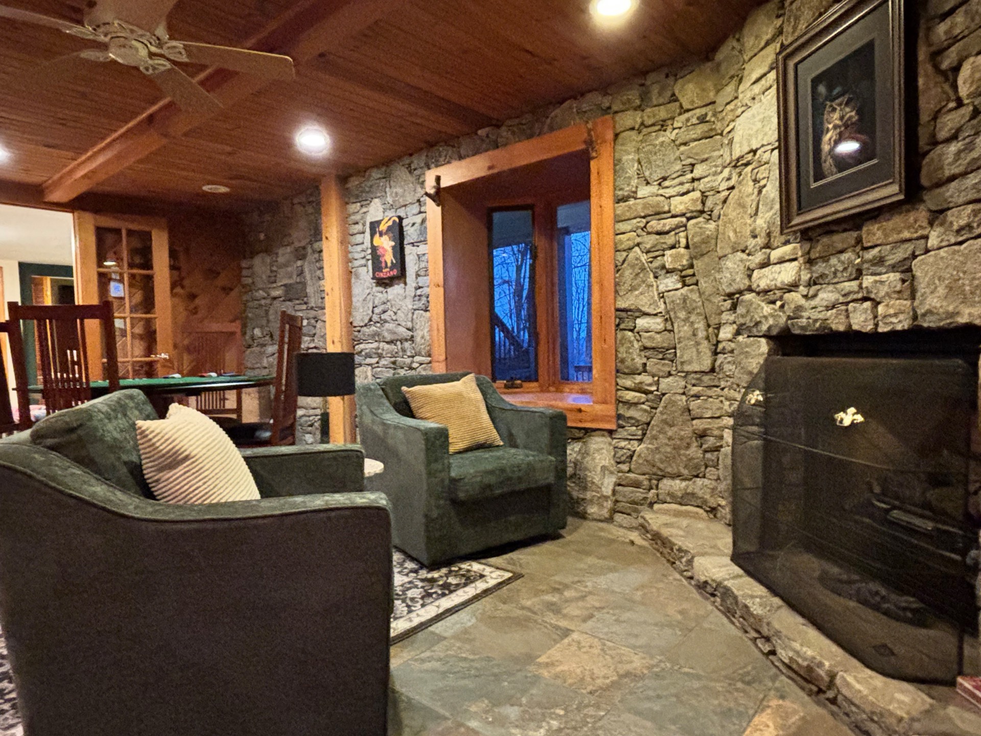 Stone wall lounge with green chairs and cedar ceiling